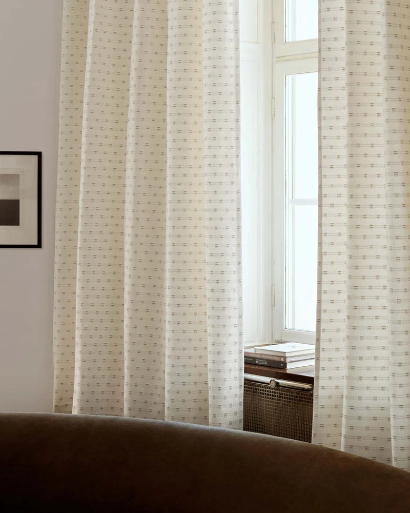 Cream woven curtains drawn back from a tall window